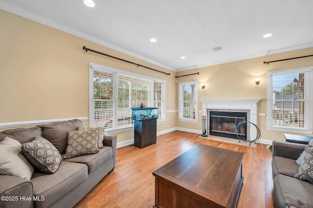 living area with ornamental molding, a fireplace with flush hearth, recessed lighting, light wood-type flooring, and baseboards
