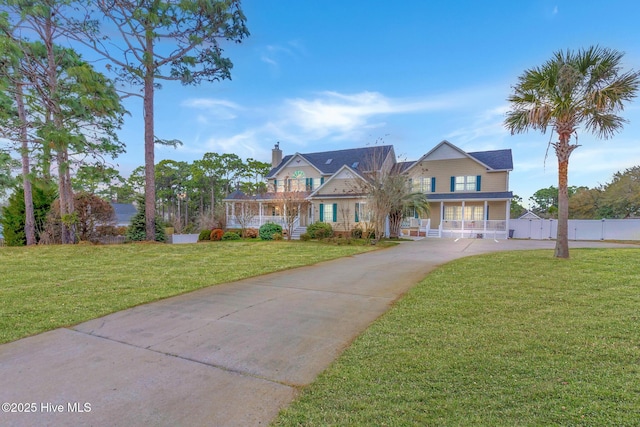 view of front of property with a front yard, fence, covered porch, and driveway