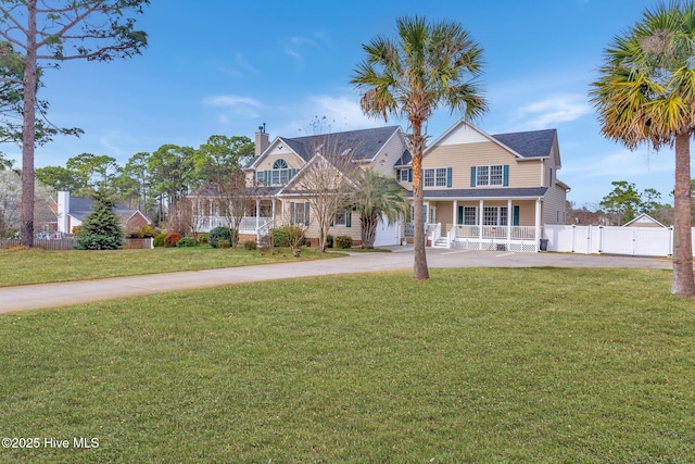 view of front facade featuring concrete driveway, fence, a front lawn, and a gate