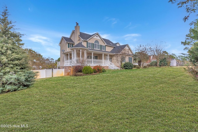 view of front of property with a front lawn, fence, covered porch, and a chimney