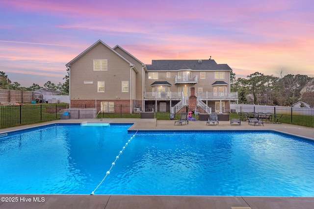 pool at dusk with a patio area, a fenced in pool, and fence