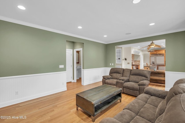 living room with crown molding, recessed lighting, a wainscoted wall, and light wood finished floors