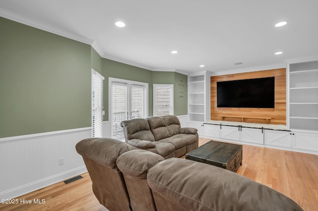 living area with light wood finished floors, wainscoting, recessed lighting, crown molding, and built in features