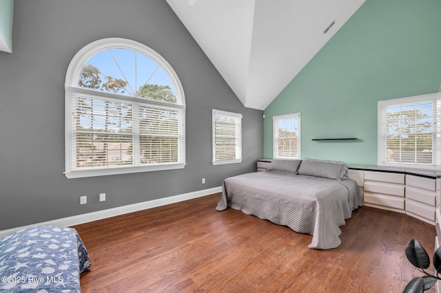 bedroom with high vaulted ceiling, wood finished floors, visible vents, and baseboards