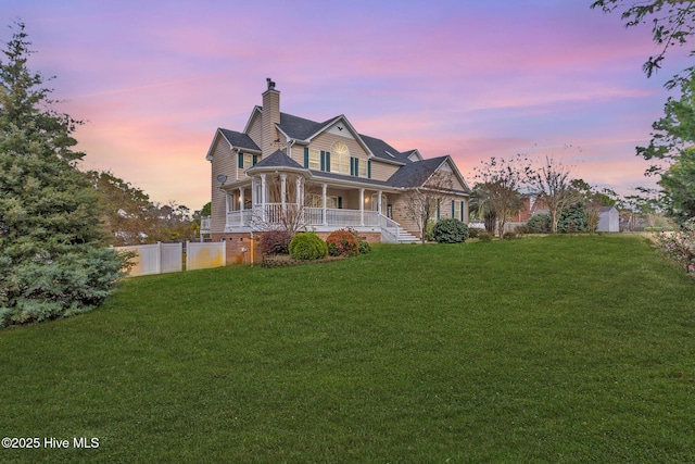 view of front of house featuring a lawn, a porch, a chimney, and fence