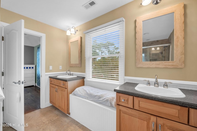 full bathroom featuring a stall shower, two vanities, and wainscoting