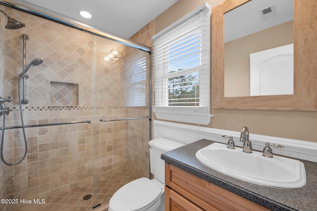 bathroom with visible vents, vanity, toilet, and a shower stall