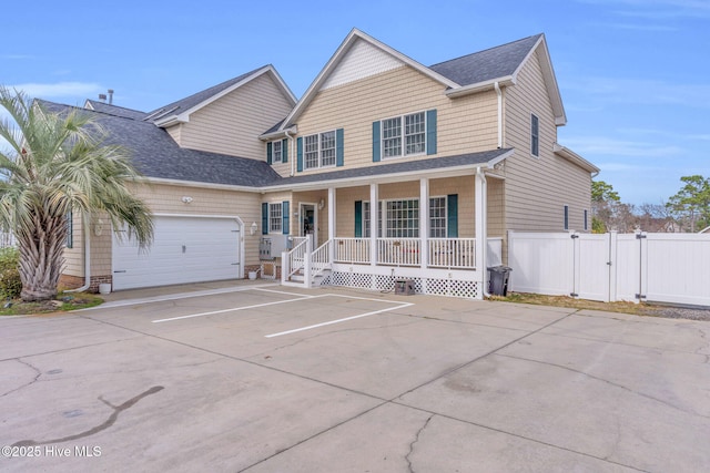 traditional home featuring fence, roof with shingles, covered porch, an attached garage, and a gate