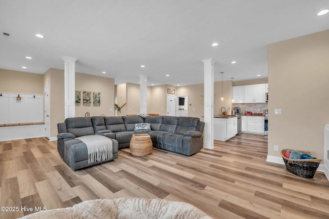 living room with decorative columns, light wood-style floors, recessed lighting, and baseboards