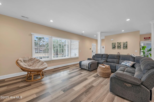living room featuring decorative columns, recessed lighting, light wood-style floors, and baseboards