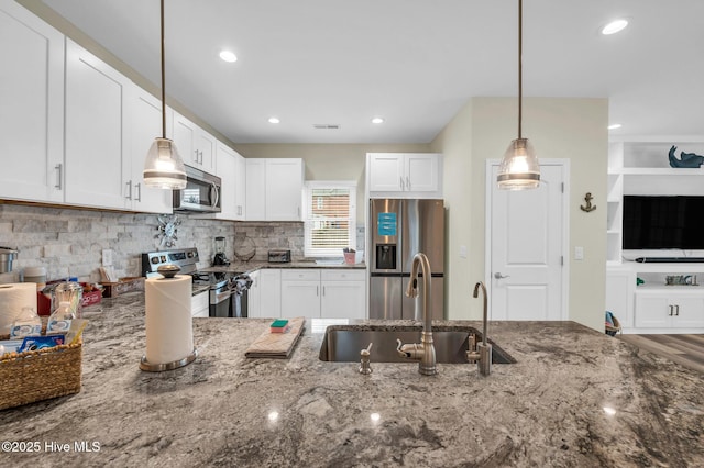kitchen with stainless steel appliances, a sink, dark stone counters, tasteful backsplash, and recessed lighting