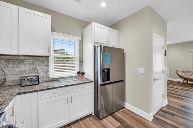 kitchen with stainless steel fridge with ice dispenser, light wood-style floors, decorative backsplash, stone countertops, and white cabinets