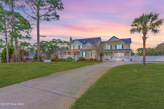 view of front of house featuring a front lawn, a porch, driveway, and fence