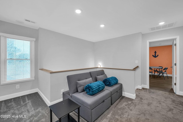 living area featuring carpet flooring, an upstairs landing, and visible vents