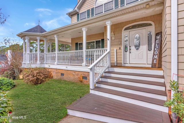 view of exterior entry with a lawn and a porch