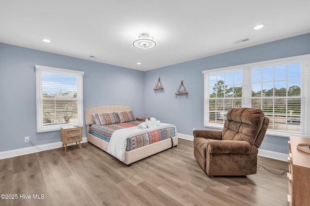 bedroom featuring wood finished floors, multiple windows, baseboards, and recessed lighting