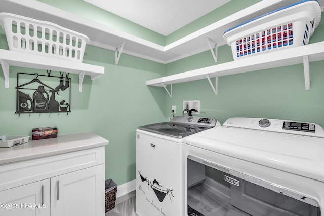 clothes washing area featuring cabinet space, baseboards, and washer and clothes dryer