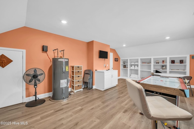 office space featuring electric water heater, vaulted ceiling, light wood-style floors, baseboards, and built in shelves
