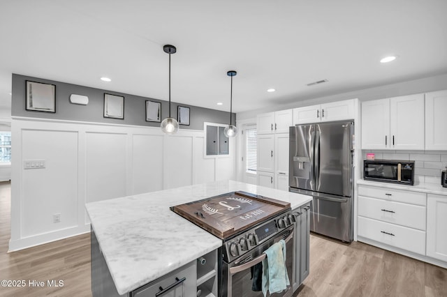 kitchen featuring stainless steel refrigerator with ice dispenser, electric range oven, white cabinetry, black microwave, and light wood finished floors