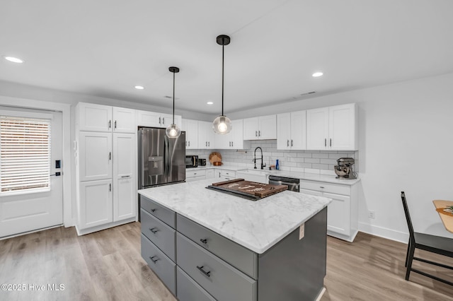 kitchen with gray cabinetry, a sink, a kitchen island, stainless steel appliances, and white cabinets