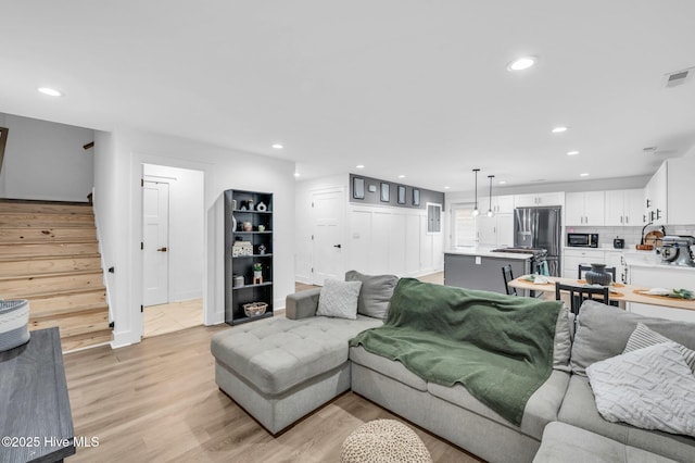 living room featuring stairway, recessed lighting, light wood-style flooring, and visible vents