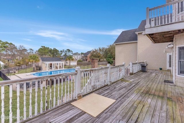 deck featuring grilling area, an outbuilding, a fenced in pool, and fence