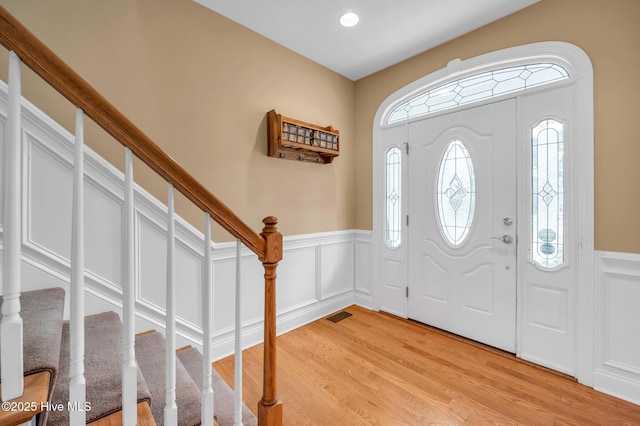 foyer featuring stairway, wainscoting, visible vents, and light wood-style floors