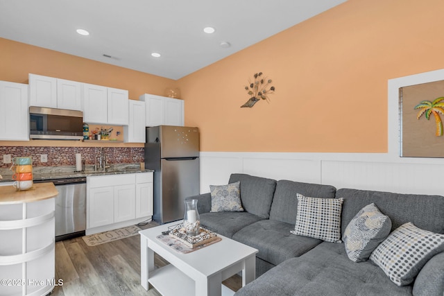 living room with light wood-style flooring, recessed lighting, visible vents, and wainscoting