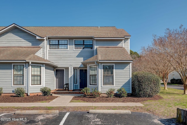 townhome / multi-family property featuring a shingled roof and uncovered parking