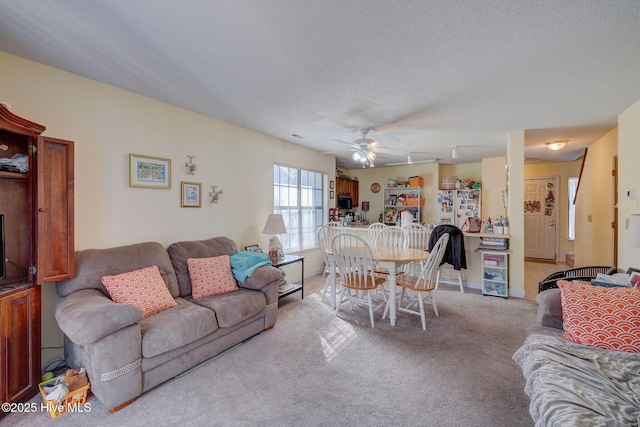 living room featuring a textured ceiling, a ceiling fan, and light colored carpet