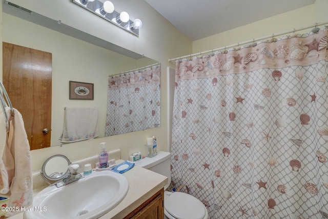 bathroom with curtained shower, visible vents, toilet, vanity, and a textured ceiling