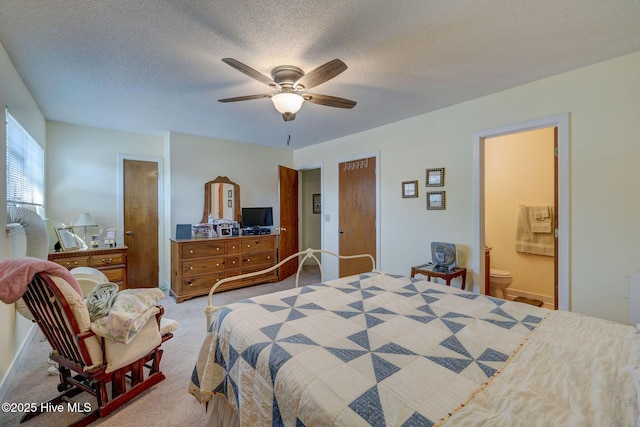 bedroom featuring carpet floors, a textured ceiling, ensuite bath, and a ceiling fan