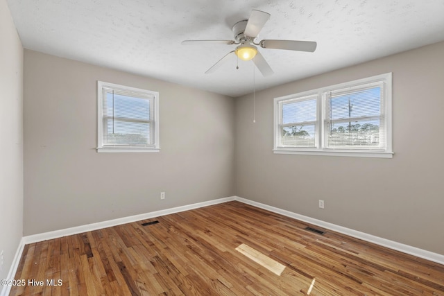 empty room featuring visible vents, baseboards, and wood finished floors