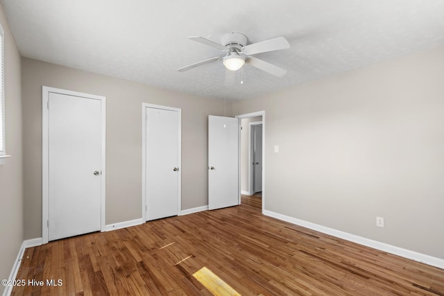 unfurnished bedroom with ceiling fan, baseboards, and wood finished floors