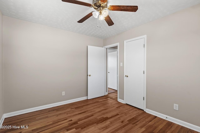 unfurnished bedroom featuring a textured ceiling, baseboards, and wood finished floors