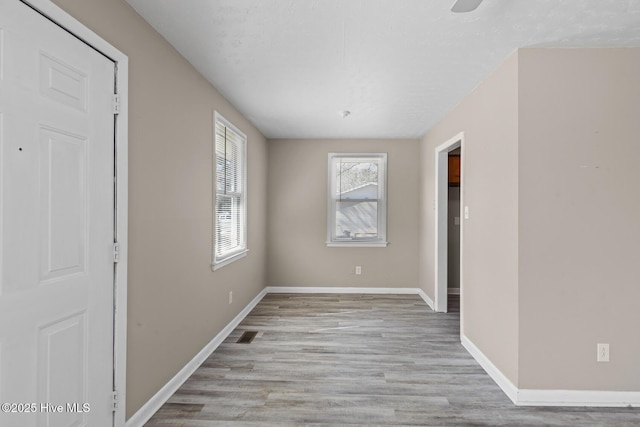 spare room featuring wood finished floors, visible vents, and baseboards