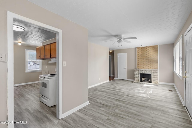 unfurnished living room with light wood finished floors, a fireplace, and baseboards