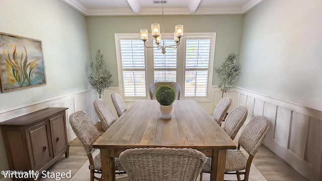 dining space with a wainscoted wall, a notable chandelier, light wood finished floors, visible vents, and beamed ceiling