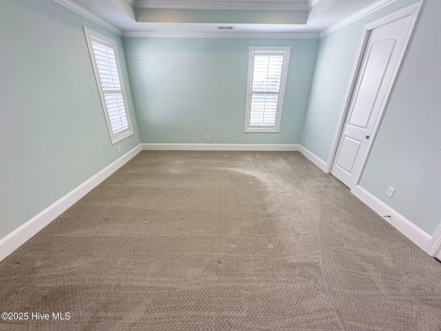 carpeted empty room featuring baseboards, visible vents, ornamental molding, and a raised ceiling