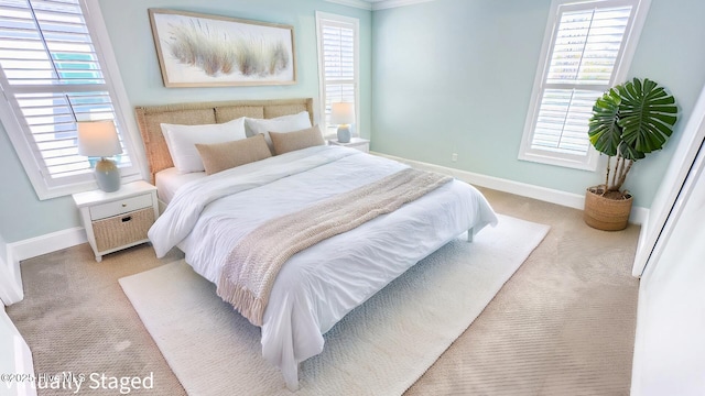 bedroom featuring multiple windows, baseboards, and light colored carpet