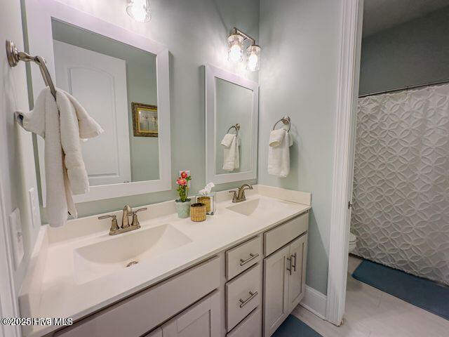 full bath featuring double vanity, a sink, toilet, and a shower with curtain