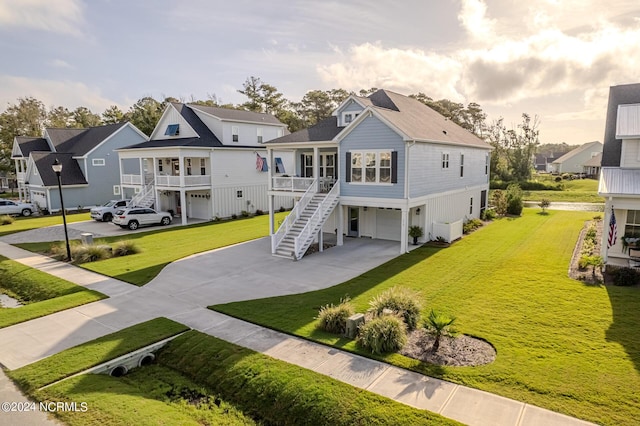 exterior space featuring a residential view, concrete driveway, a front lawn, and stairs