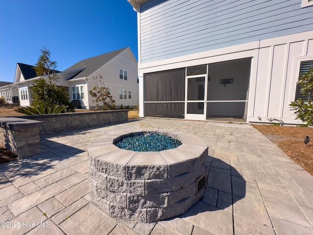 view of patio with a sunroom and an outdoor fire pit