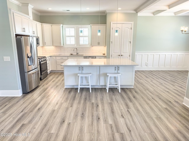 kitchen featuring a kitchen island, appliances with stainless steel finishes, a kitchen breakfast bar, light countertops, and a sink