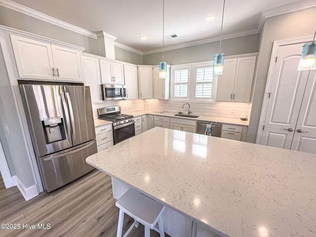 kitchen with crown molding, appliances with stainless steel finishes, backsplash, and a sink