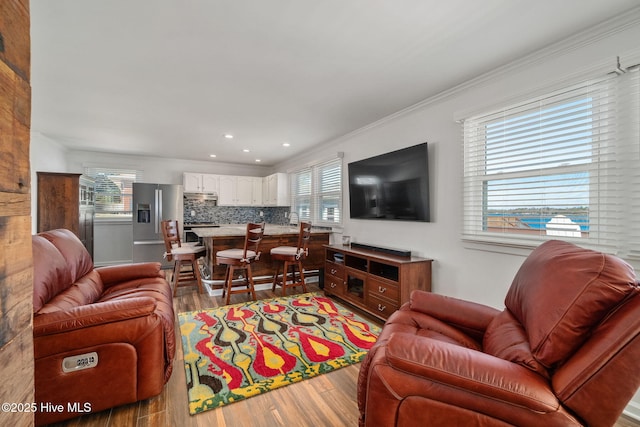 living area featuring a healthy amount of sunlight, ornamental molding, wood finished floors, and recessed lighting