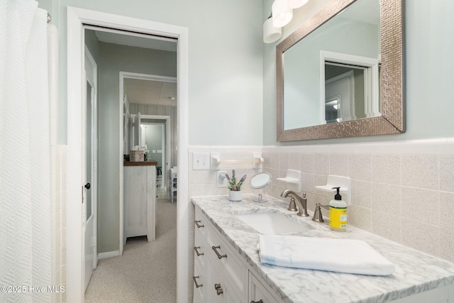 bathroom featuring tile walls, a wainscoted wall, and vanity