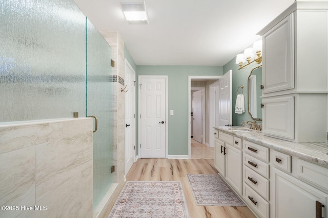 bathroom with baseboards, visible vents, wood finished floors, vanity, and a shower stall