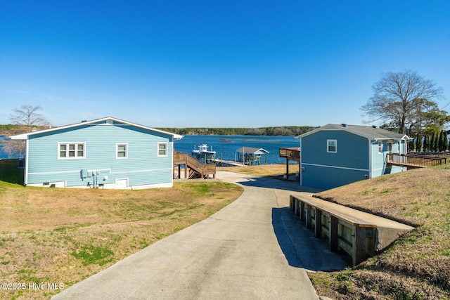 exterior space featuring stairs, a yard, a water view, and driveway