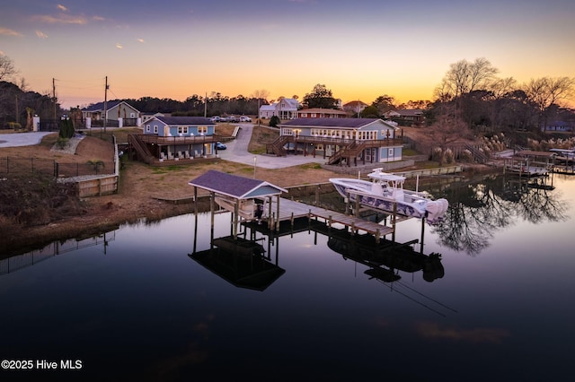 view of dock featuring a water view, boat lift, and fence